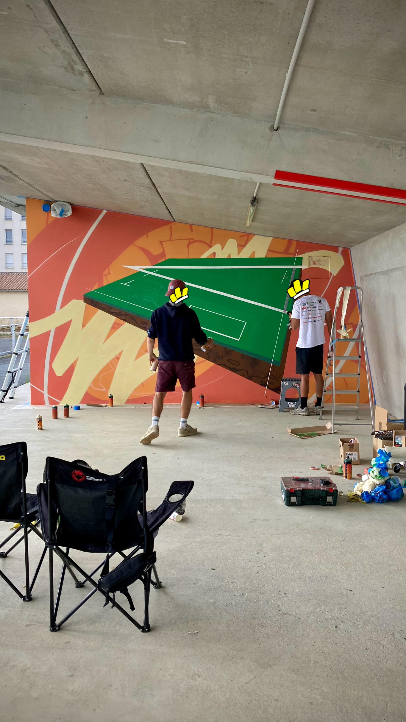 Artistes réalisant une fresque street art représentant un terrain multisport dans un équipement sportif à Floirac.