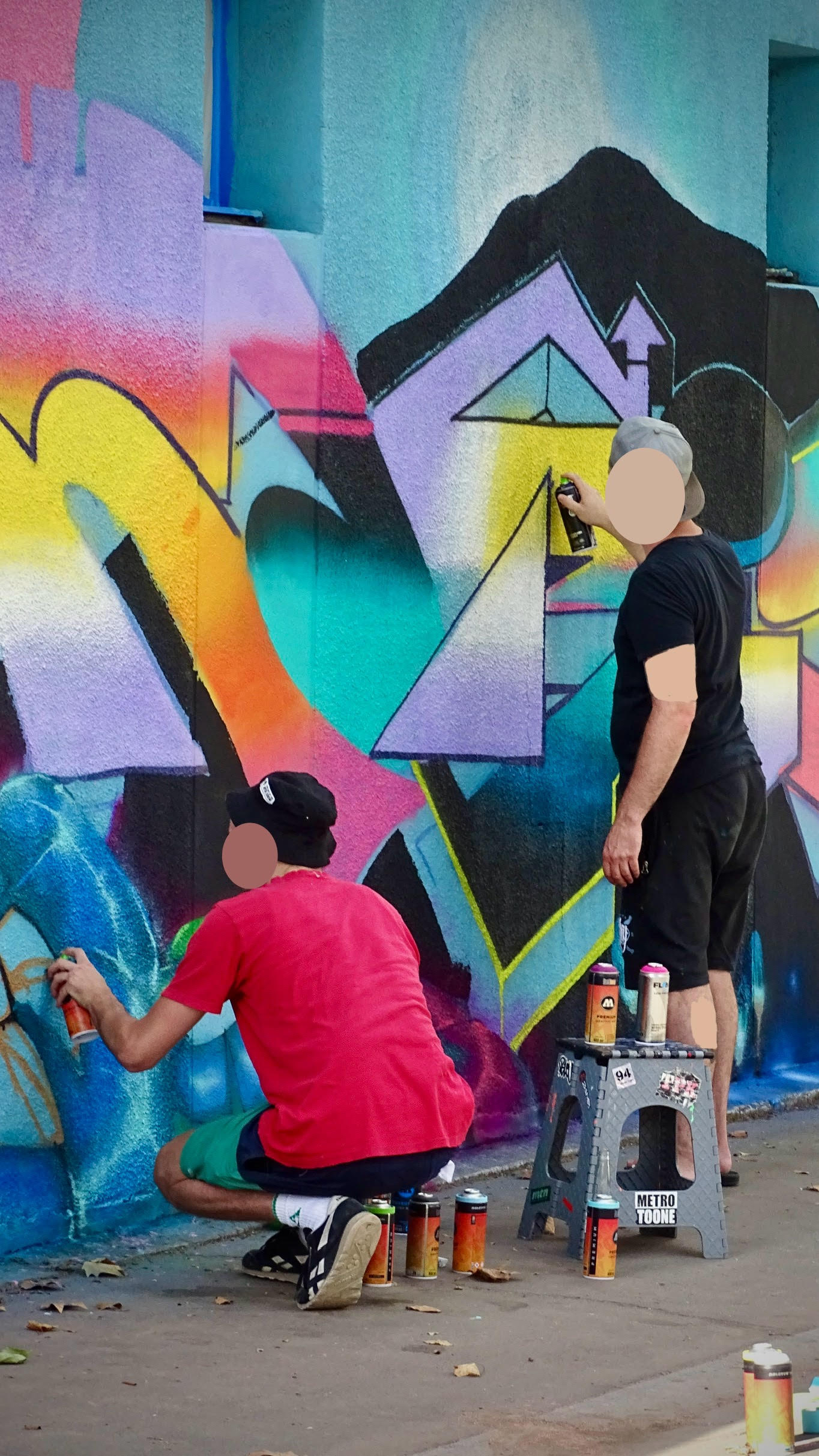 Artistes réalisant une fresque graffiti colorée lors de la JAM D’ARC 25 à Cenon avec bombes de peinture.