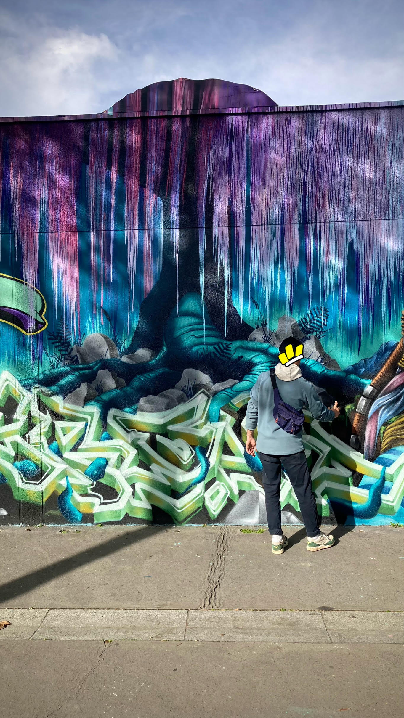 Artiste réalisant les derniers détails d’un arbre lumineux inspiré d’Avatar sur une fresque murale