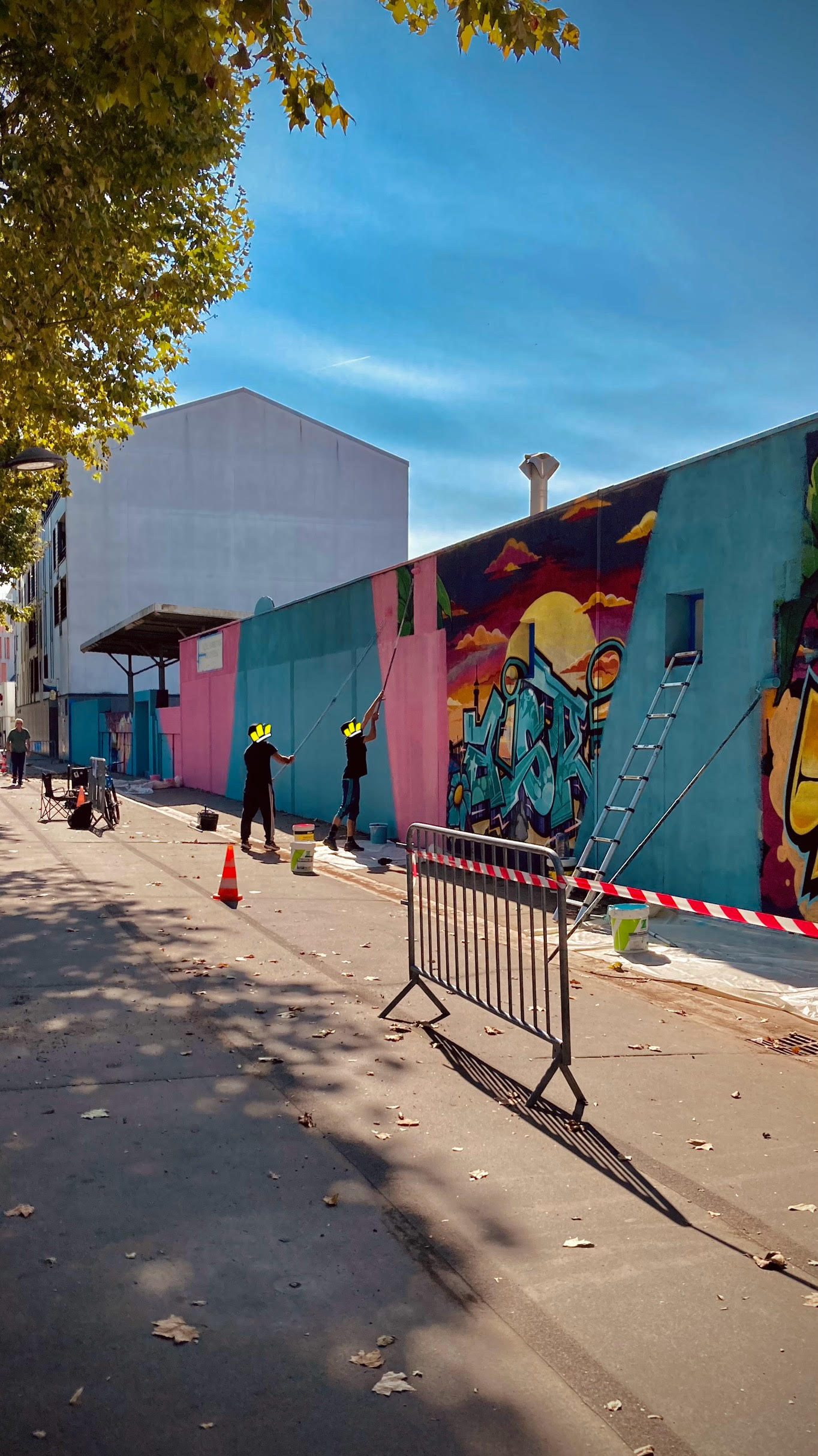 Vue d’ensemble d’un chantier de fresque murale avec artistes, matériel et mur en cours de transformation artistique
