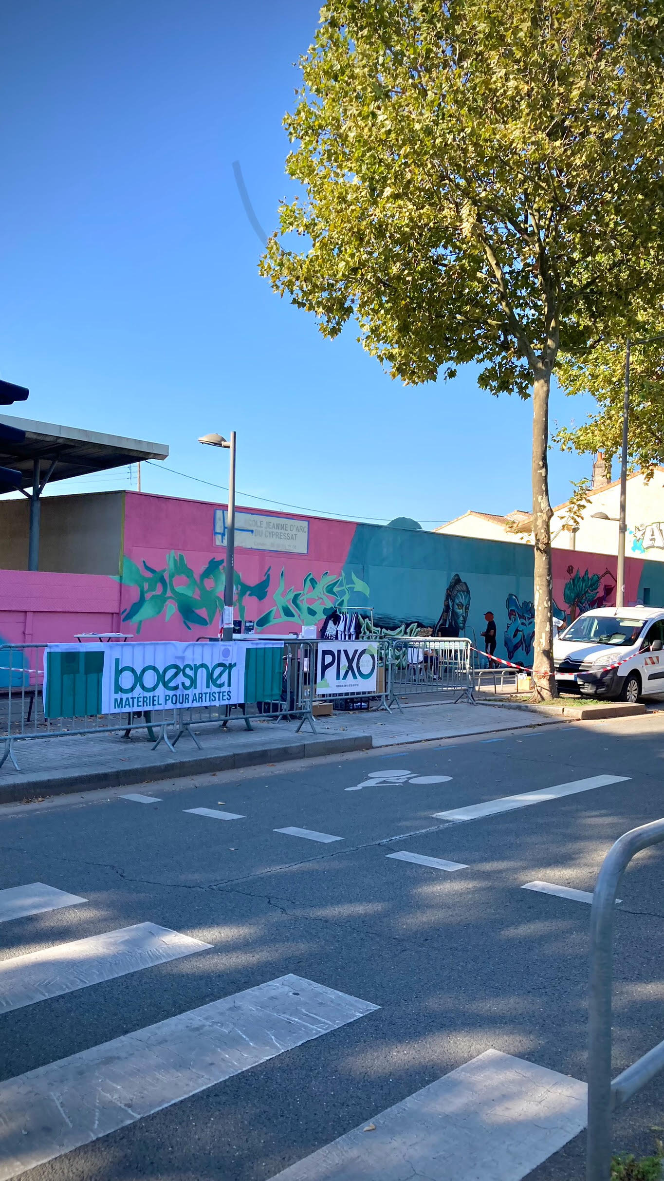 Mur extérieur en cours de transformation artistique avec logos partenaires et fresque en progression lors d’un événement street art