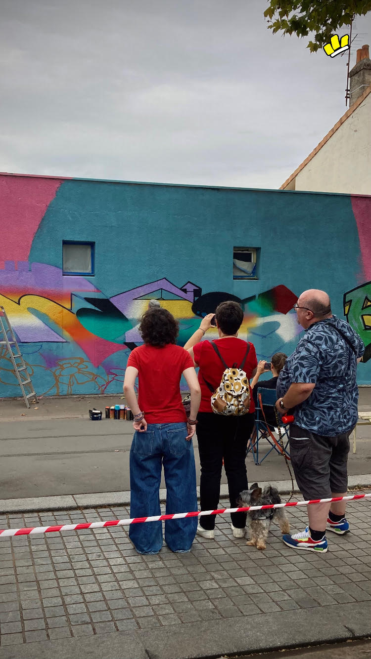 Spectateurs observant la création d’une fresque murale colorée inspirée d’Avatar lors d’un événement street art