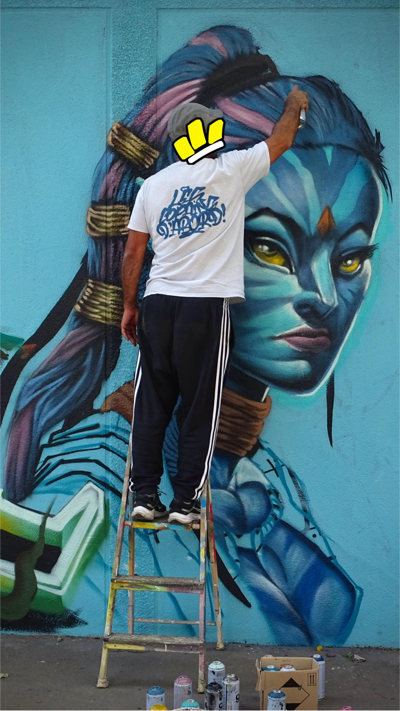 Artiste réalisant le visage d’un personnage Avatar en peinture murale avec bombe de graffiti