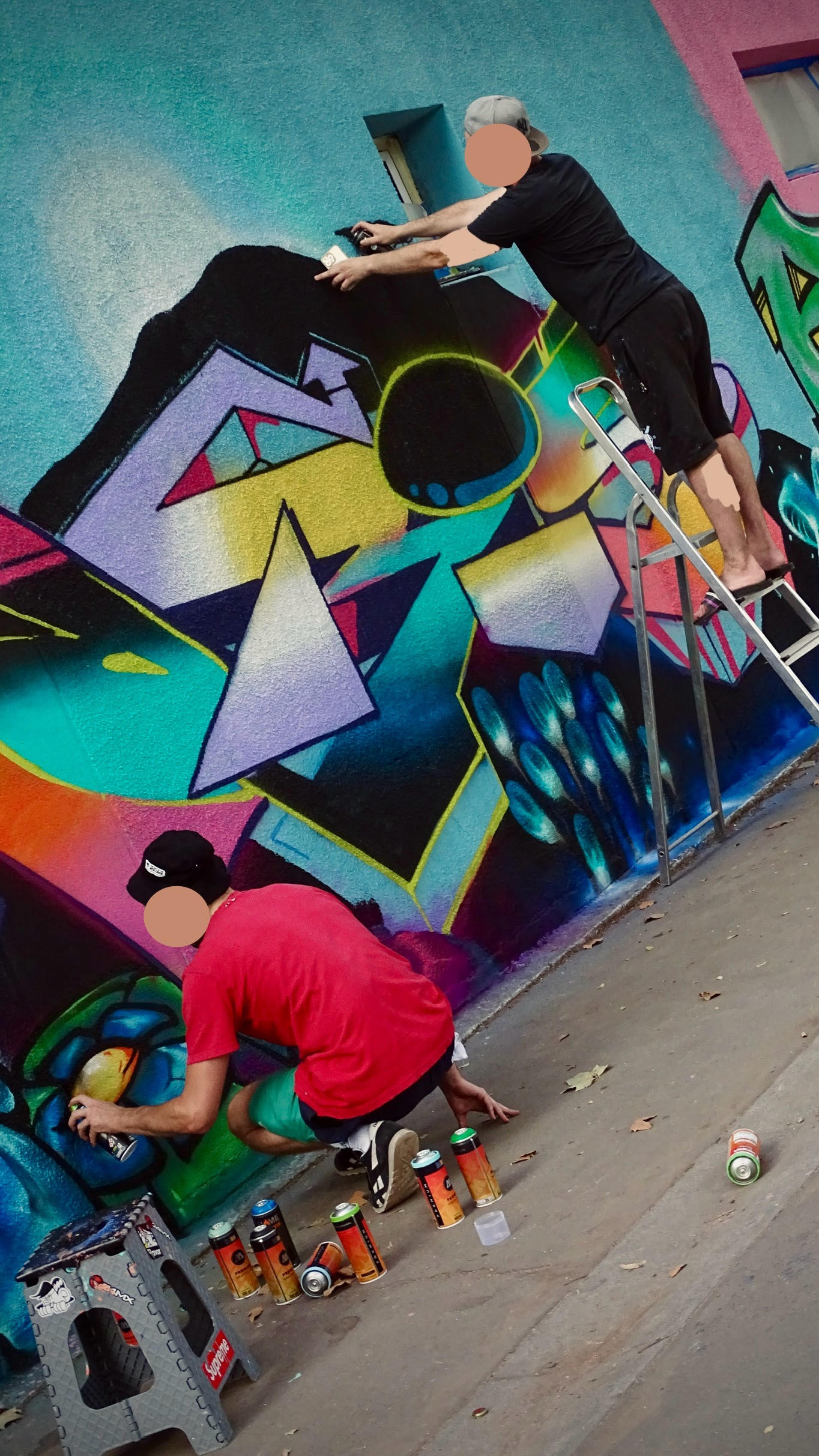 Artistes appliquant des dégradés et contours sur une fresque murale avec bombes de peinture