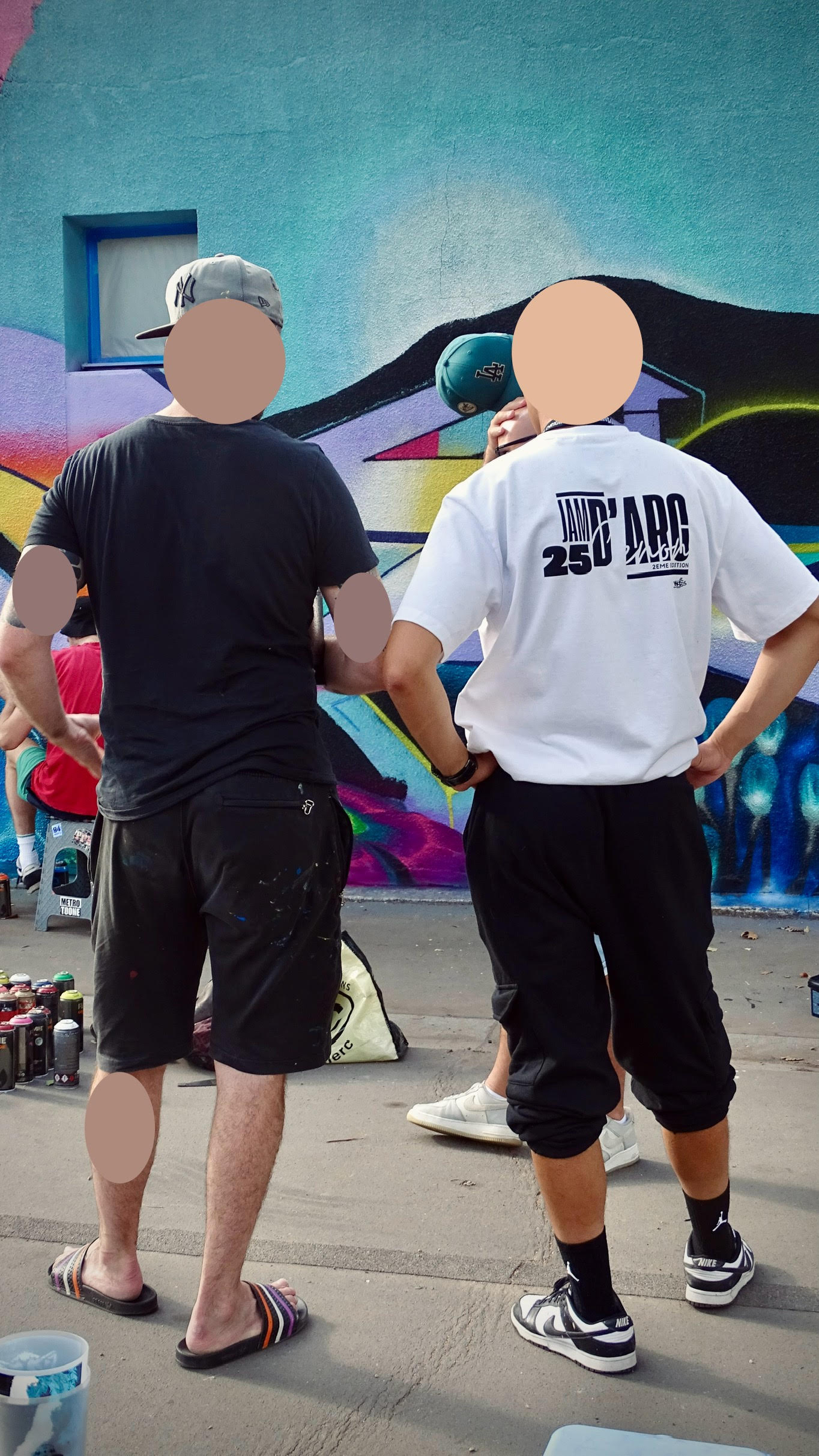 Artiste et organisateur observant et analysant une fresque graffiti en cours pour ajuster la composition