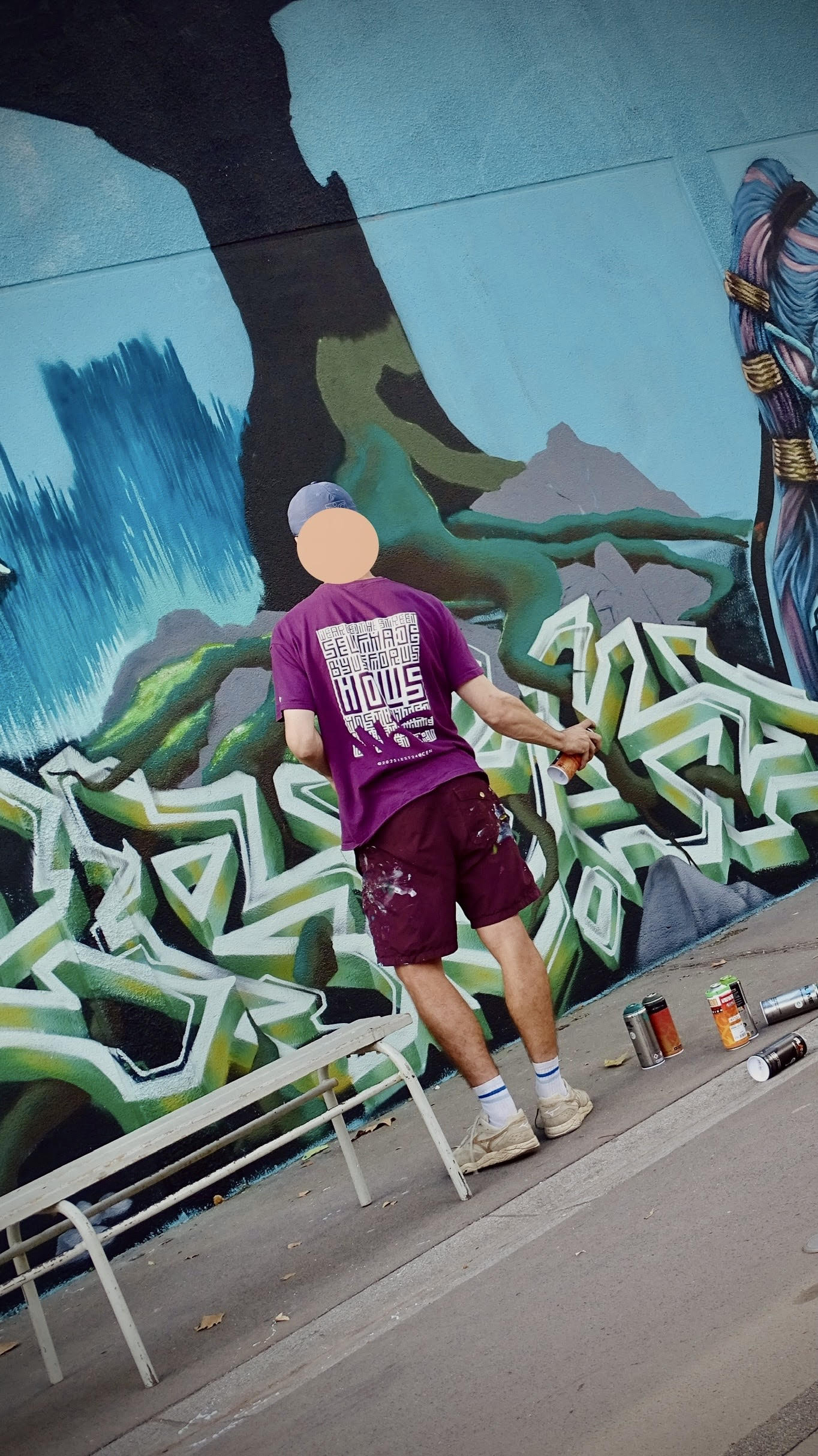 Artiste peignant un décor de paysage stylisé avec graffiti sur un mur extérieur