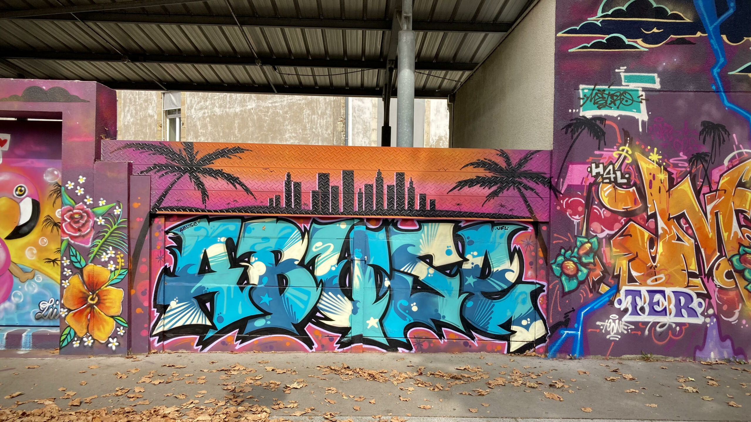 Lettrage graffiti avec skyline urbaine et fond coloré dégradé.