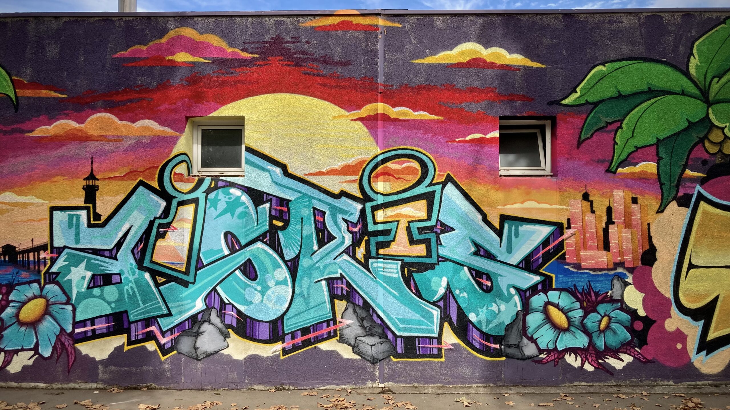 Lettrage graffiti bleu avec skyline et coucher de soleil en arrière-plan.