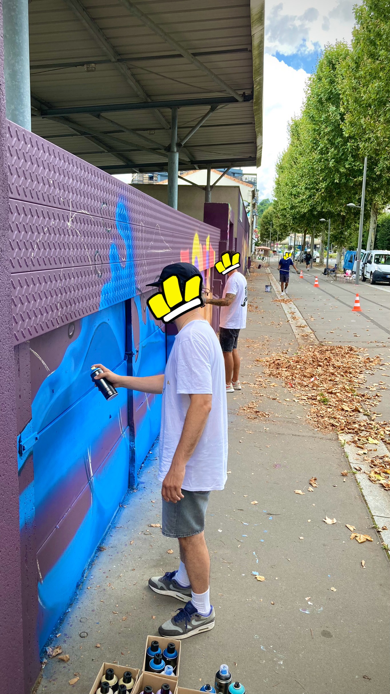 Plusieurs artistes réalisant une fresque graffiti sur un mur urbain à Cenon.