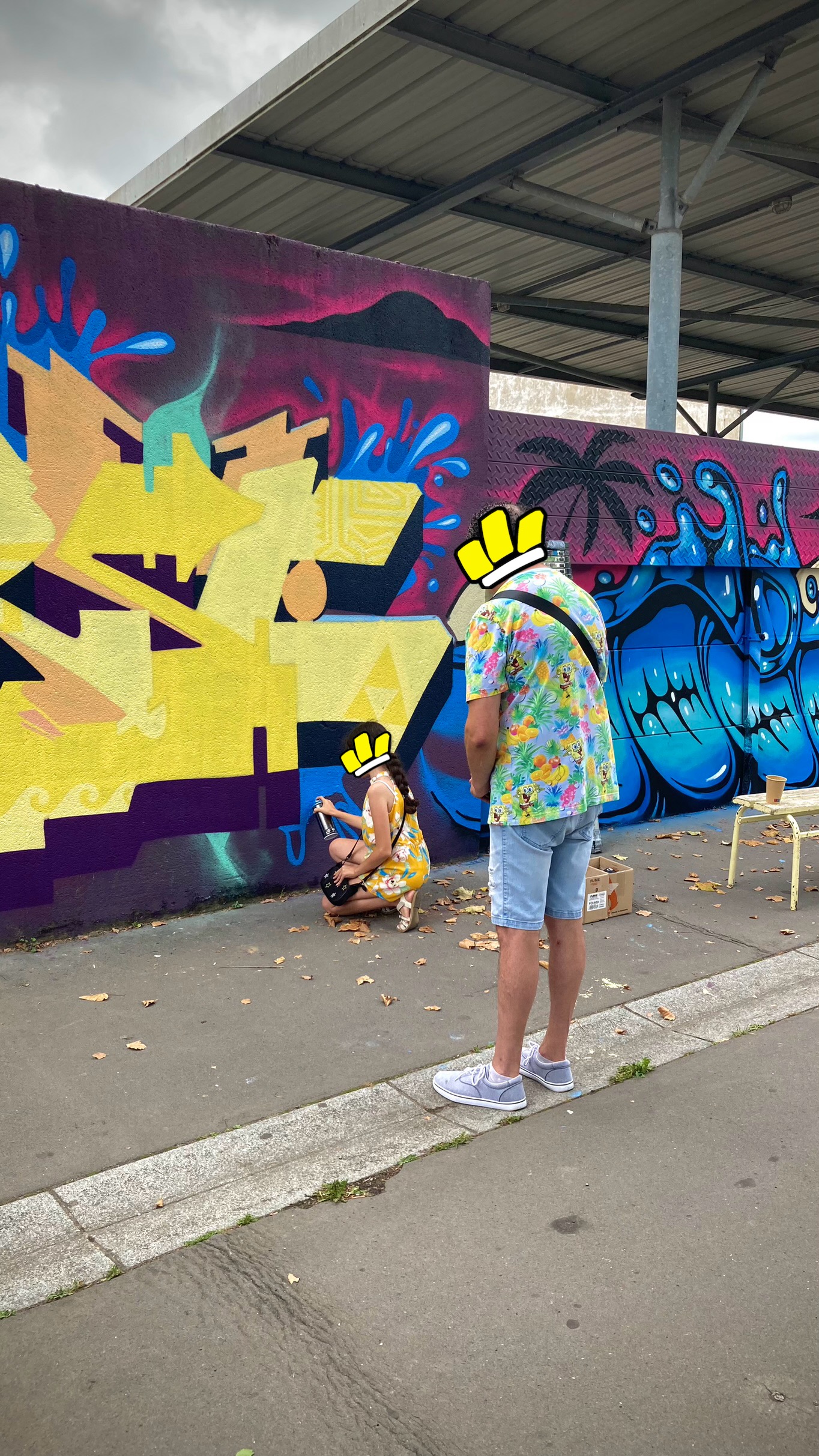Une enfant apprend le graffiti encadrée par un artiste lors d’une fresque.