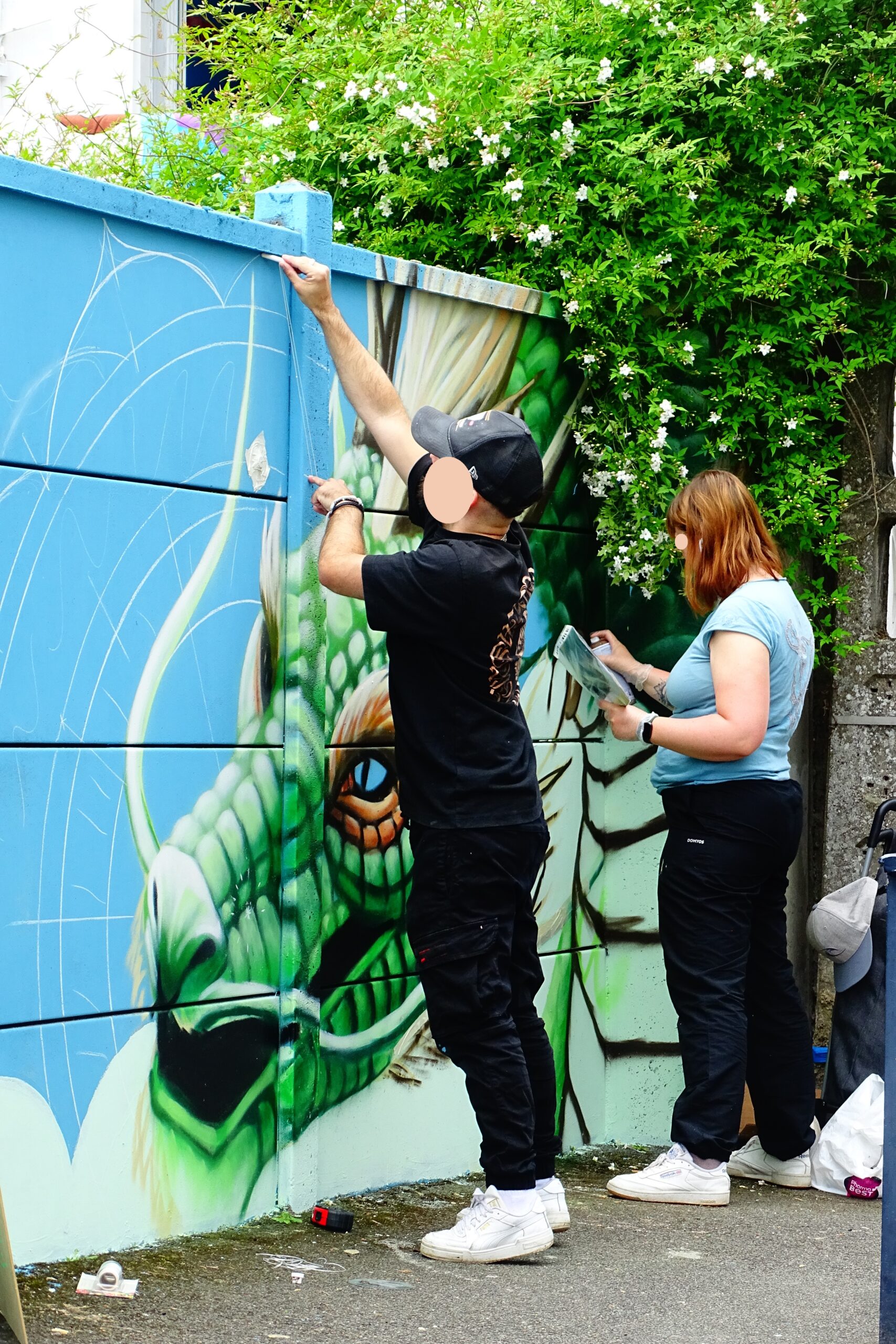 Artistes dessinant dragon et mandala calligraphique sur mur street art graffiti