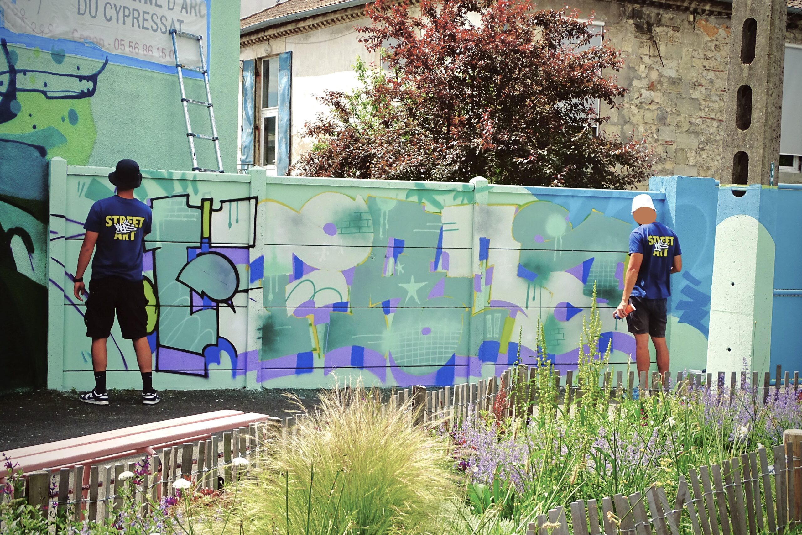Artistes réalisant lettrage graffiti sur mur école Jeanne d’Arc Cenon