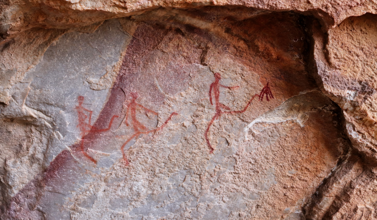 Figures humaines rouges peintes sur une paroi rocheuse dans un site d’art rupestre ancien.