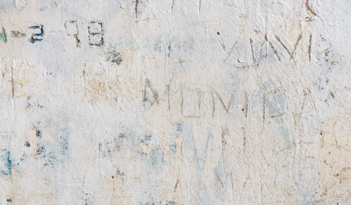 Inscriptions, lettres et marques anciennes gravées sur une paroi claire et patinée.