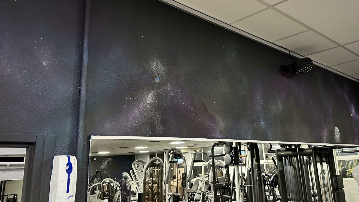 Mur décoratif cosmos avec nébuleuses et planètes dans une salle de fitness moderne