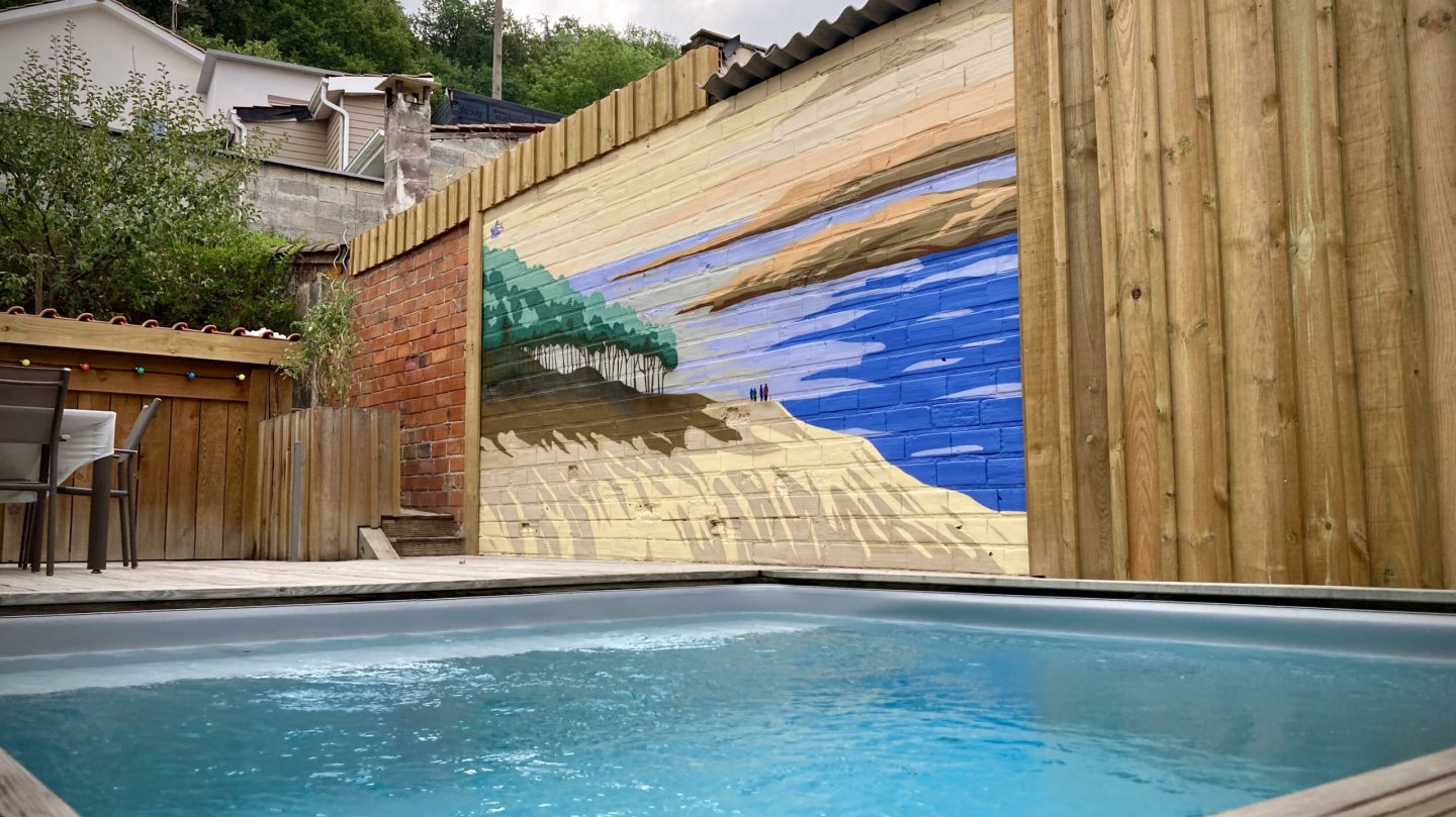 Vue panoramique de fresque murale Banc d’Arguin dans un jardin privé avec terrasse en bois et piscine.