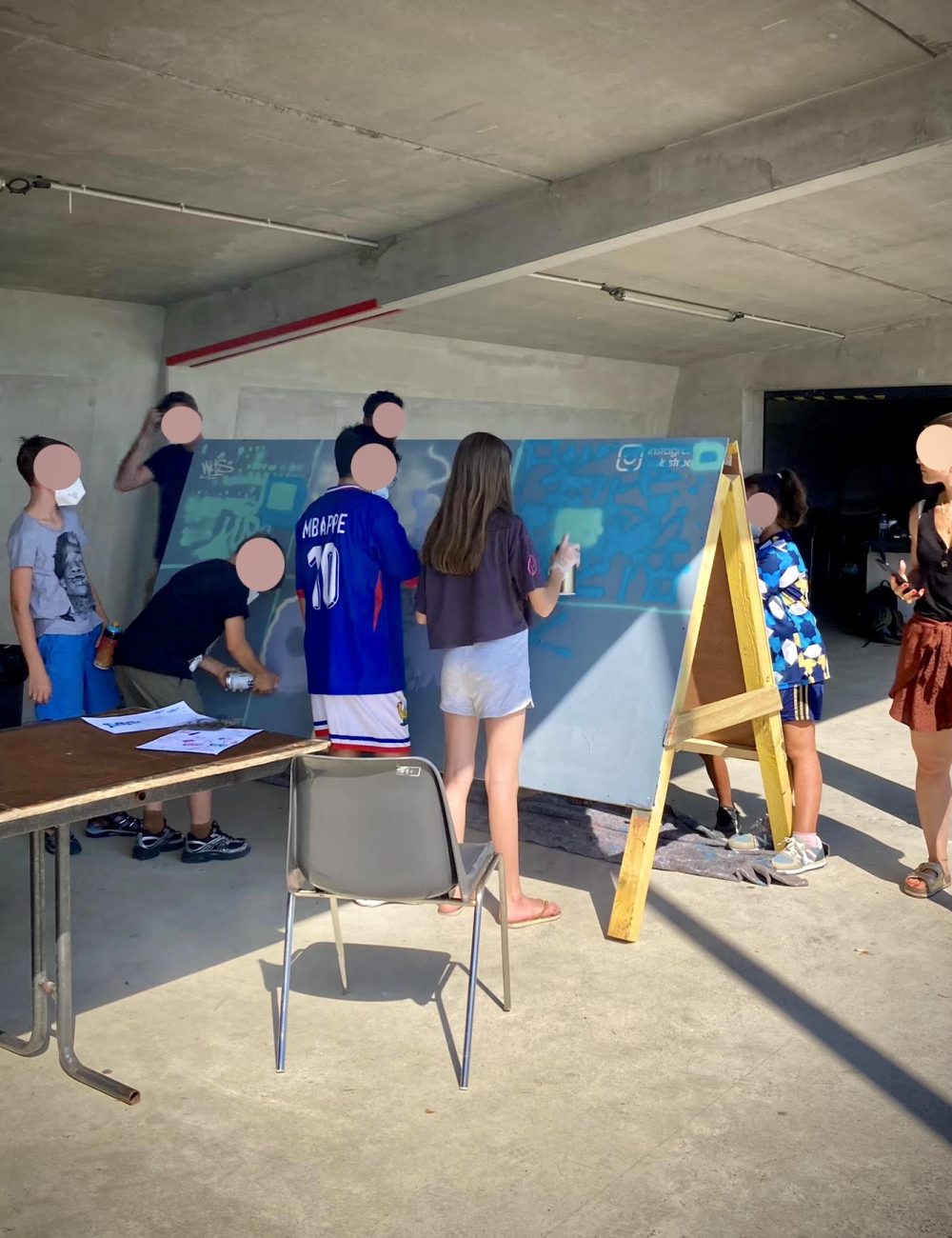Enfants réalisant des graffitis à la bombe sur un panneau pendant un atelier CAP33 animé par WOLS Street Art à Floirac.
