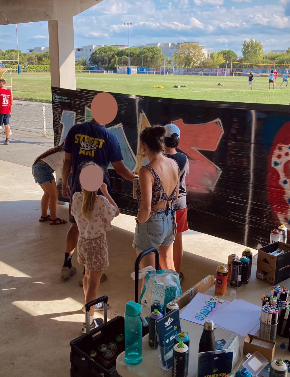 Enfants et adultes peignent un graffiti collectif lors d’un atelier WOLS Street Art pour CAP33 à Floirac.