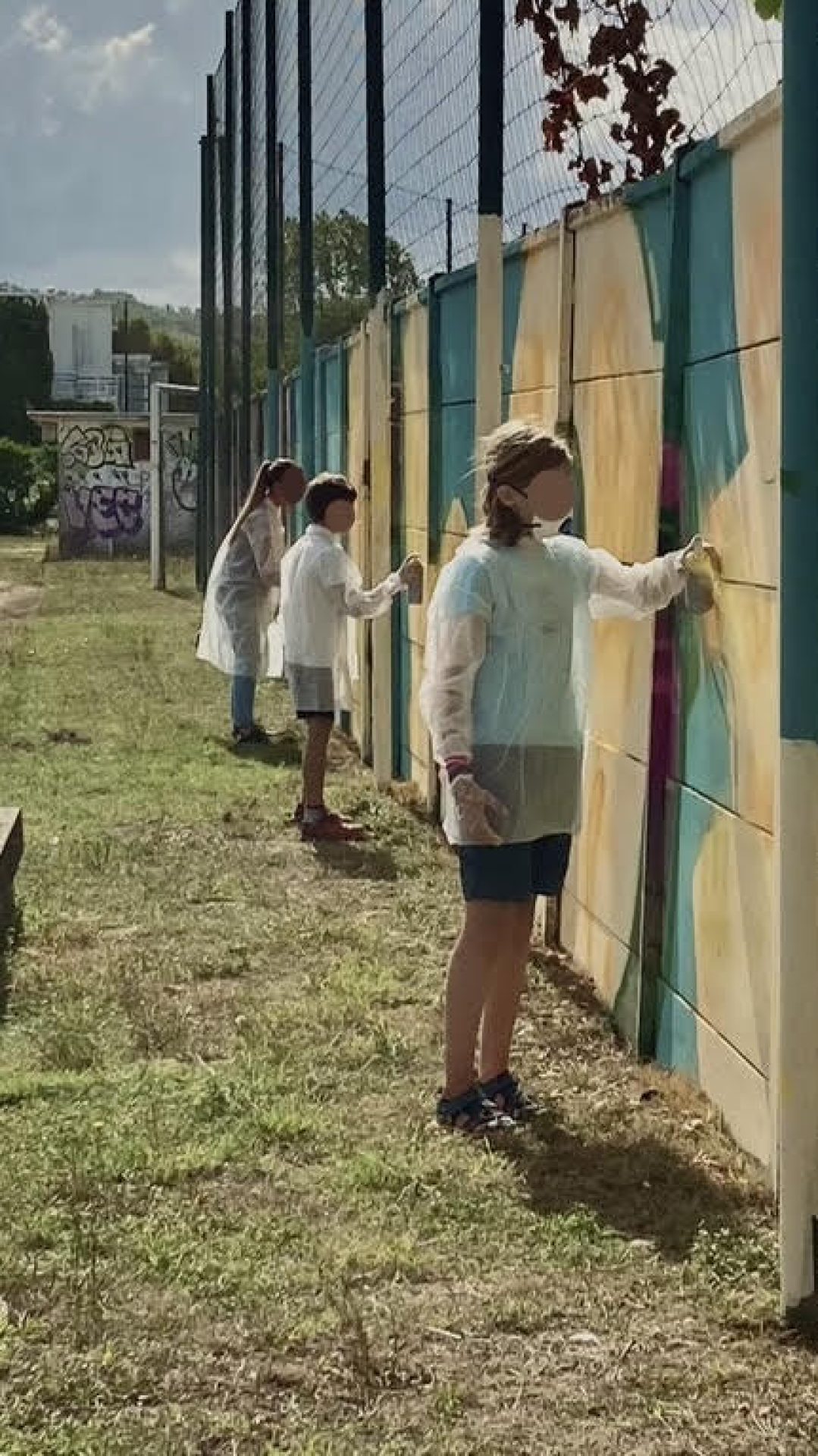 Participants peignant à la bombe le lettrage graffiti FLOIRAC lors d’une œuvre participative au stade Jean-Raymond Guyon à Floirac.