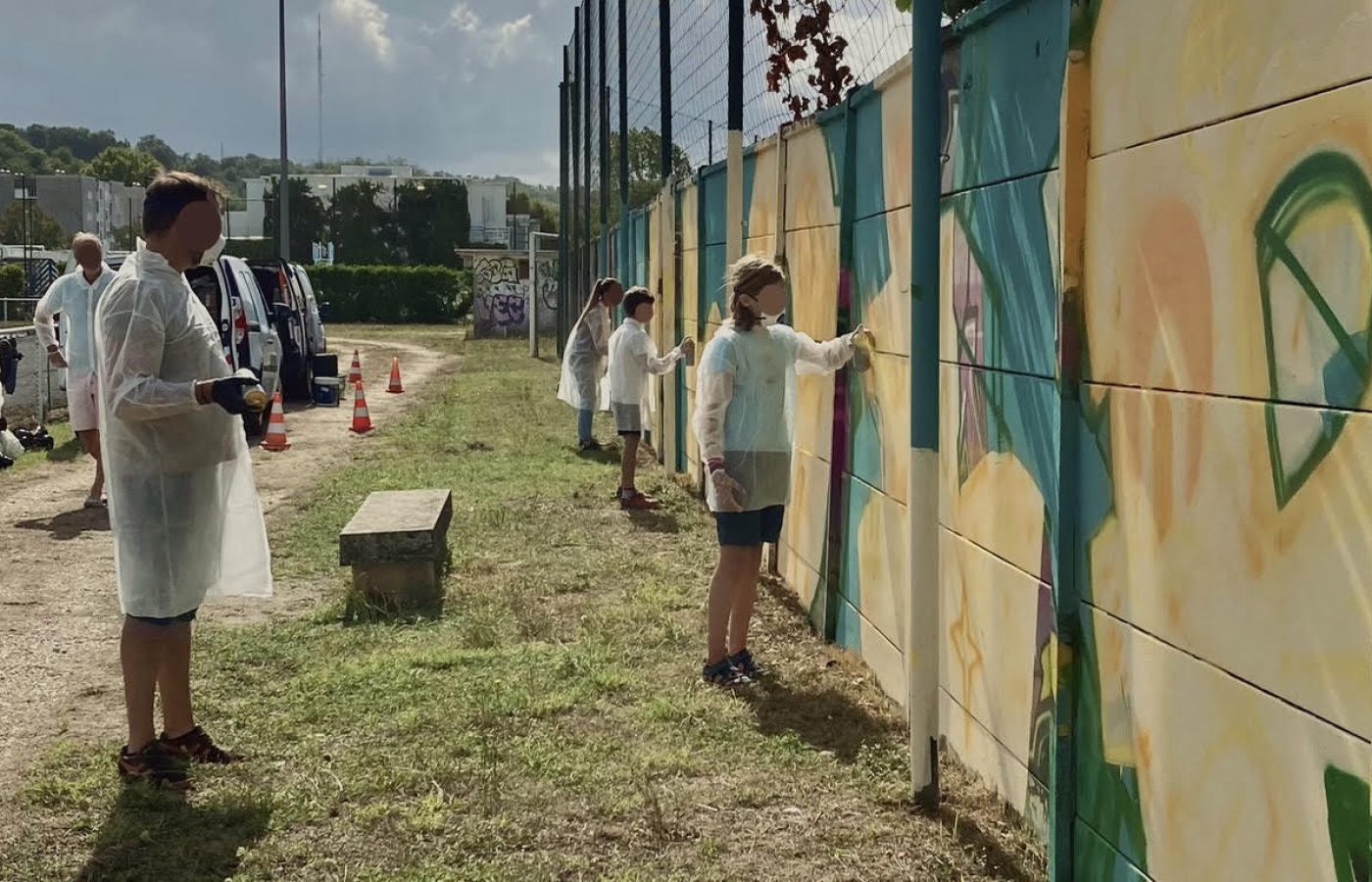 Participants peignant à la bombe le lettrage graffiti FLOIRAC lors d’une œuvre participative au stade Jean-Raymond Guyon à Floirac.