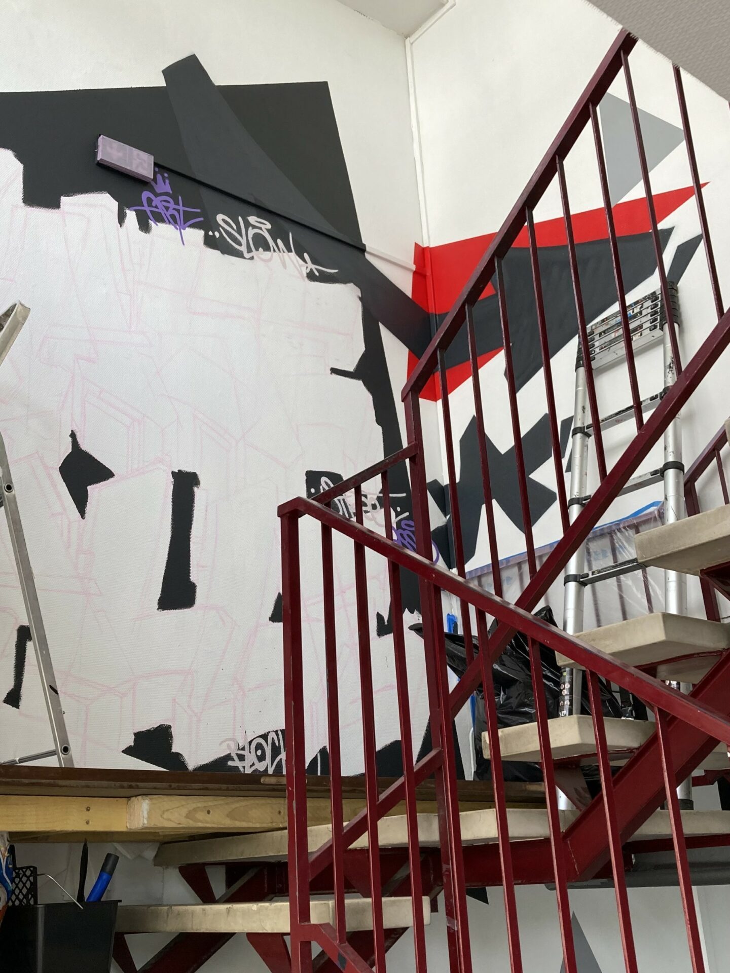 Vue latérale d’une fresque graffiti en cours de réalisation dans une cage d’escalier à Bordeaux.