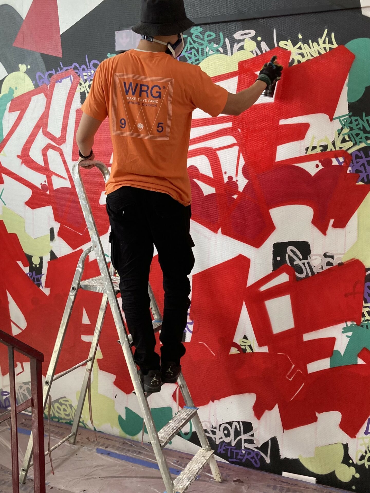 Artiste réalisant une fresque graffiti sur un mur intérieur lors d’un chantier participatif aux Aubiers à Bordeaux.