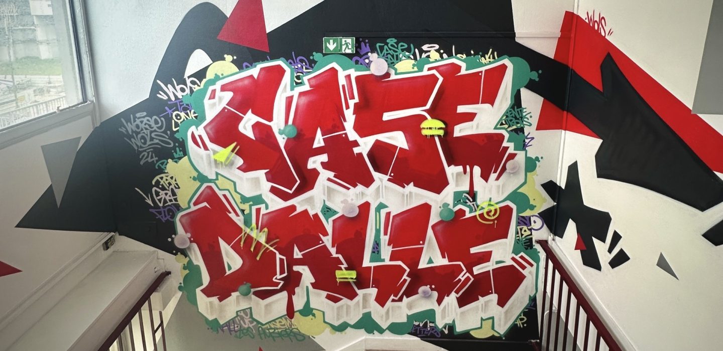 Vue complète de la fresque graffiti Case Dalle dans une cage d’escalier du quartier des Aubiers.
