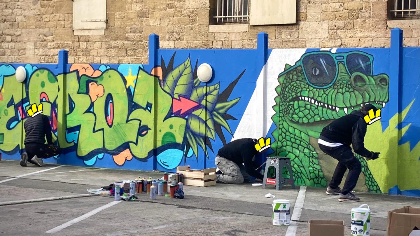 Artistes réalisant une fresque graffiti sur le parking Zolpan Bordeaux avec lettrage vert, feuillage tropical et crocodile street art.