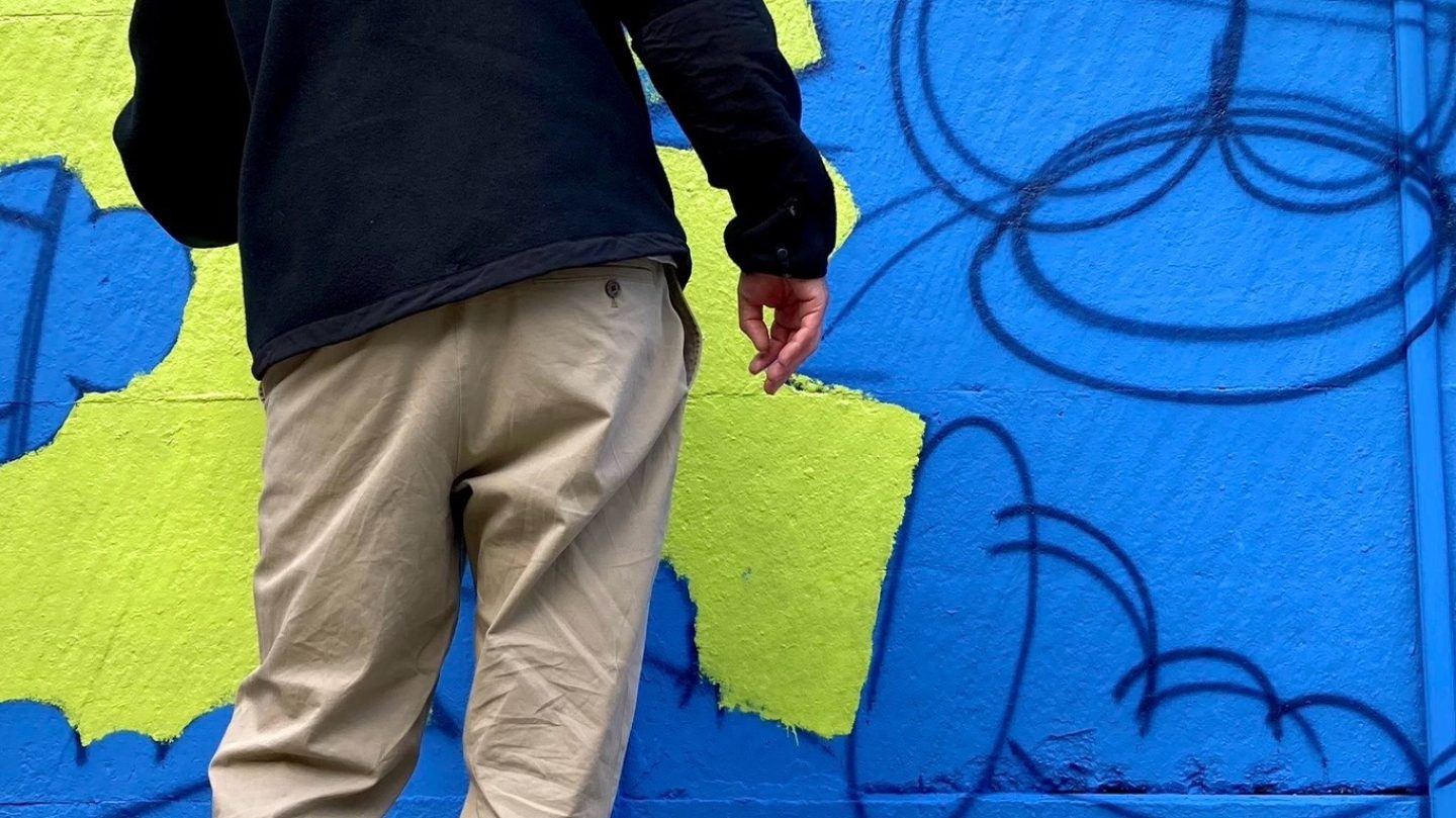 Artiste graffeur appliquant de la peinture verte sur une fresque graffiti en cours de création sur un mur extérieur à Bordeaux.