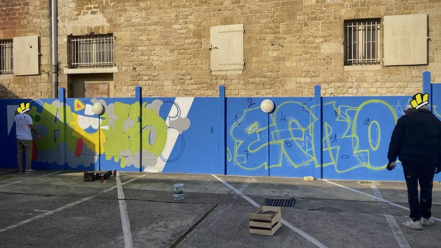 Artistes graffeurs réalisant des lettrages graffiti colorés sur un mur extérieur à Bordeaux.