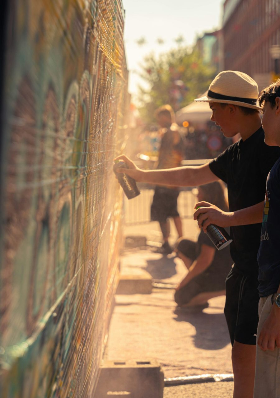Initiation graffiti en extérieur avec adolescents réalisant une fresque street art à la bombe aérosol lors d’un atelier urbain.