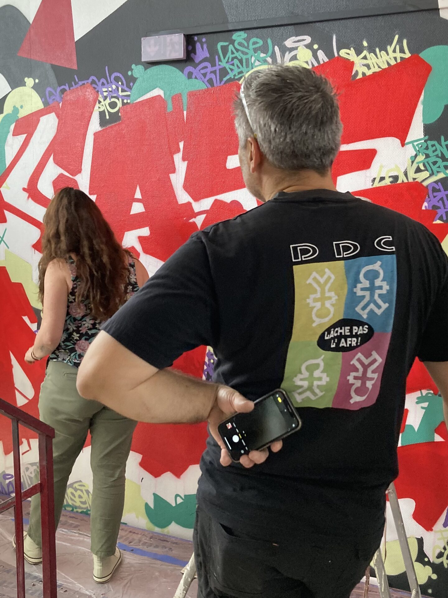 Participants observant la réalisation d’une fresque graffiti dans le cadre d’un chantier participatif à Bordeaux.
