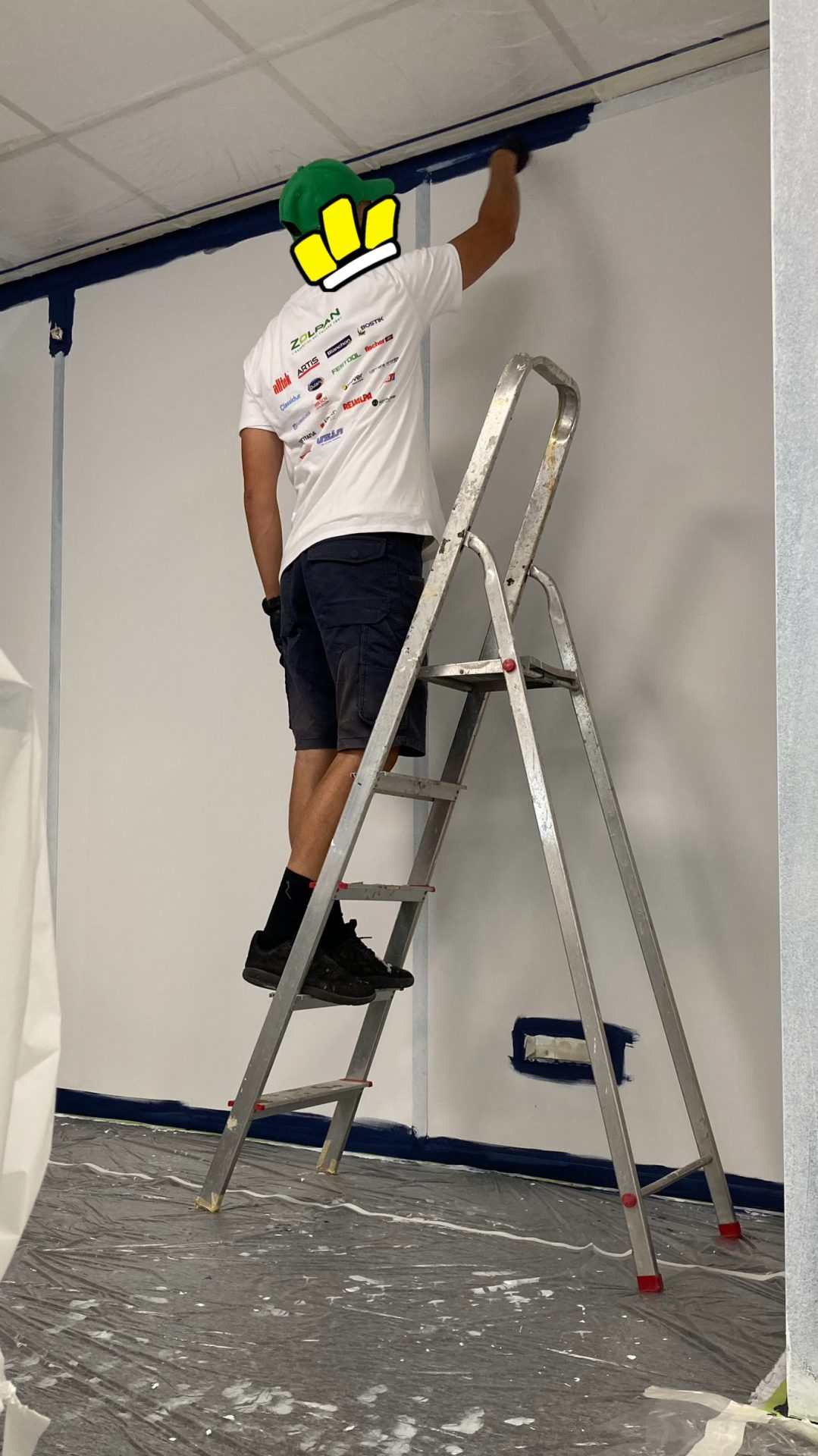 Artiste peignant une fresque murale dans un espace intérieur dédié à une équipe e-sport.