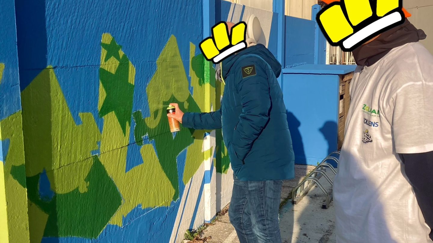 Participant utilisant une bombe de peinture lors d’une initiation graffiti sur le parking Zolpan Bordeaux avec encadrement artistique.