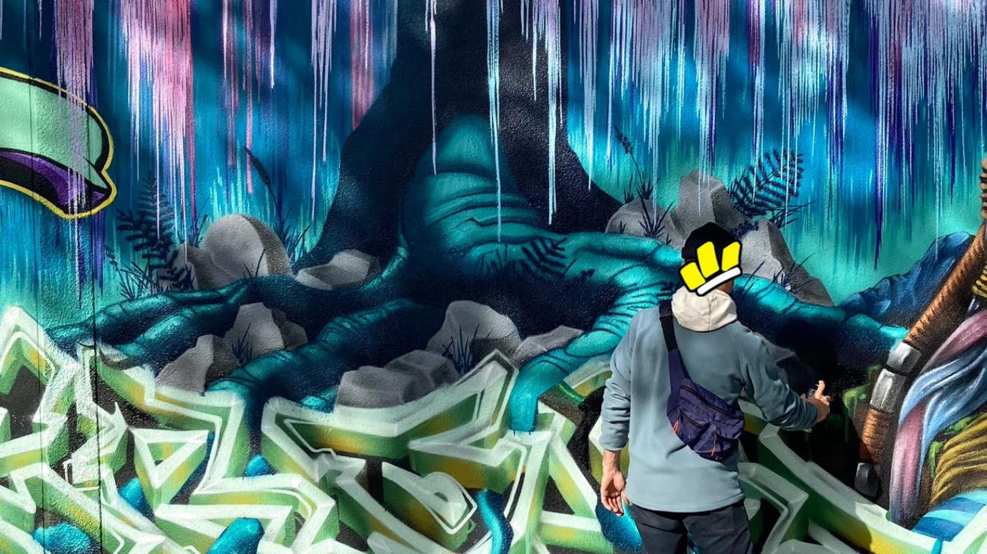 Artiste réalisant les derniers détails d’un arbre lumineux inspiré d’Avatar sur une fresque murale