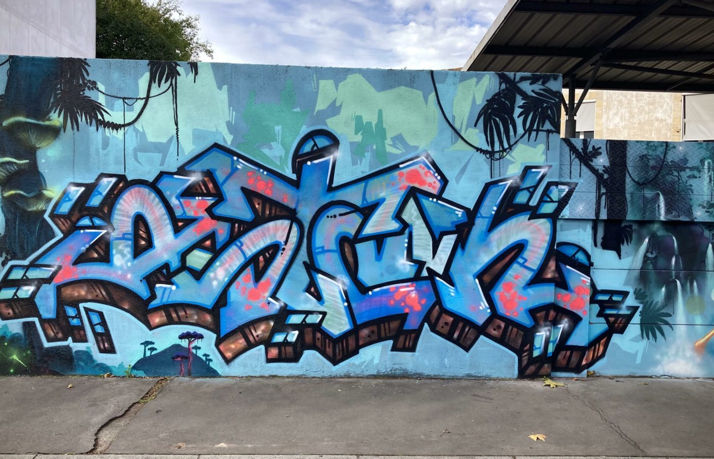 Graffiti central bleu avec effets lumineux sur fresque murale immersive Avatar