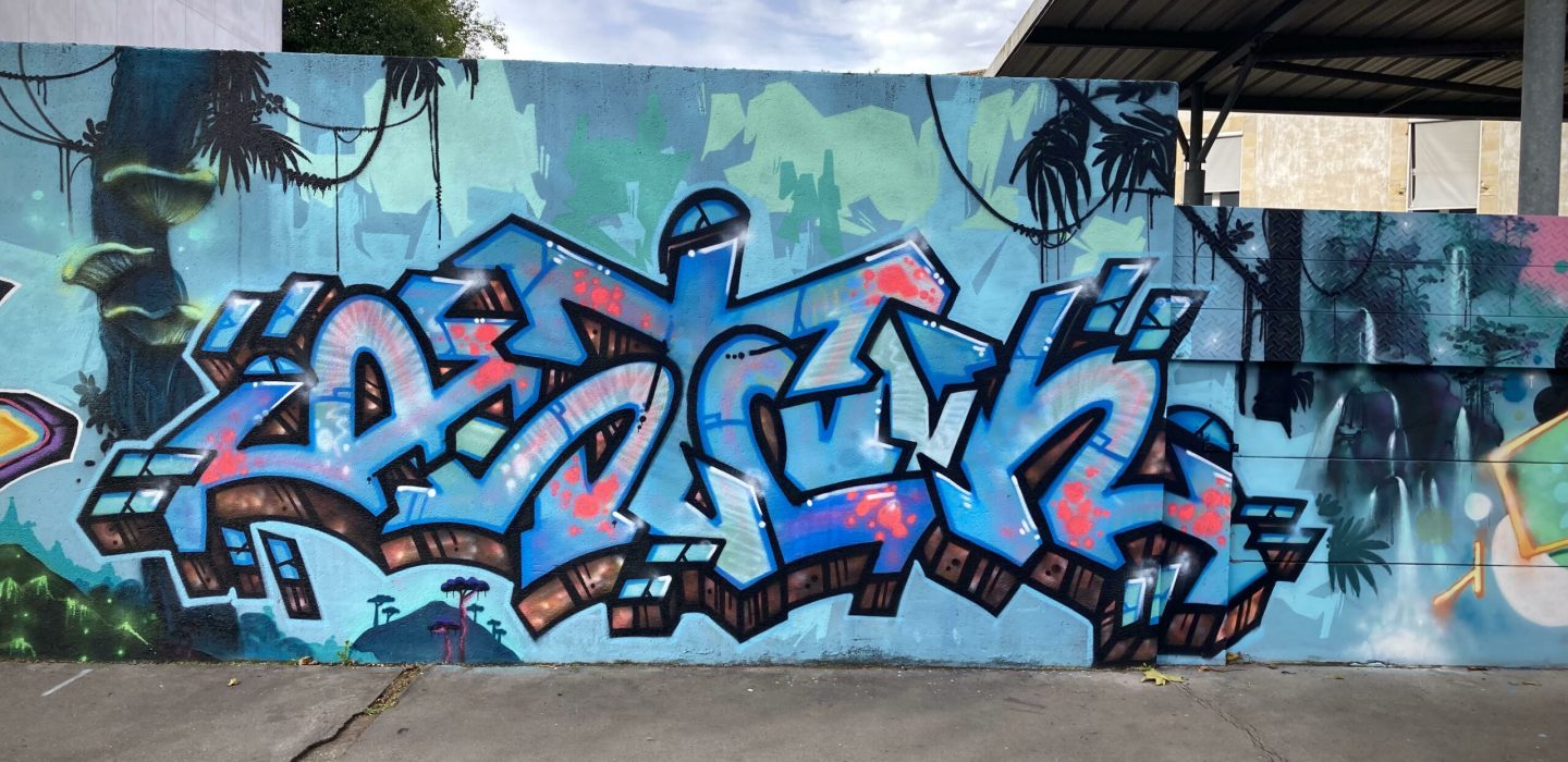 Graffiti central bleu avec effets lumineux sur fresque murale immersive Avatar