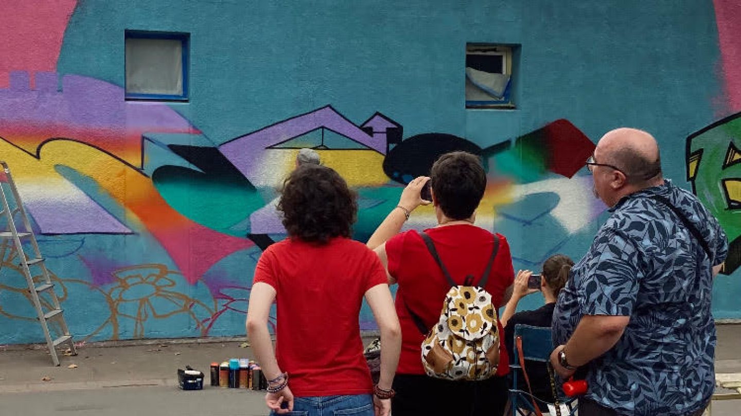Spectateurs observant la création d’une fresque murale colorée inspirée d’Avatar lors d’un événement street art
