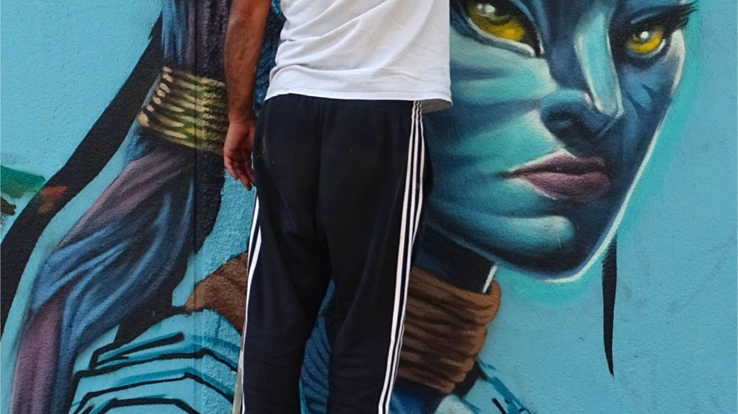Artiste réalisant le visage d’un personnage Avatar en peinture murale avec bombe de graffiti