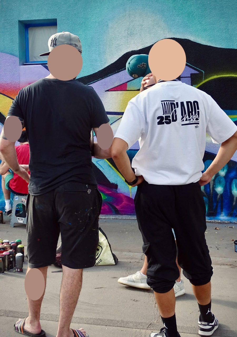Graffeur et organisateur observant une fresque graffiti en cours de réalisation lors de la JAM D'ARC 25.