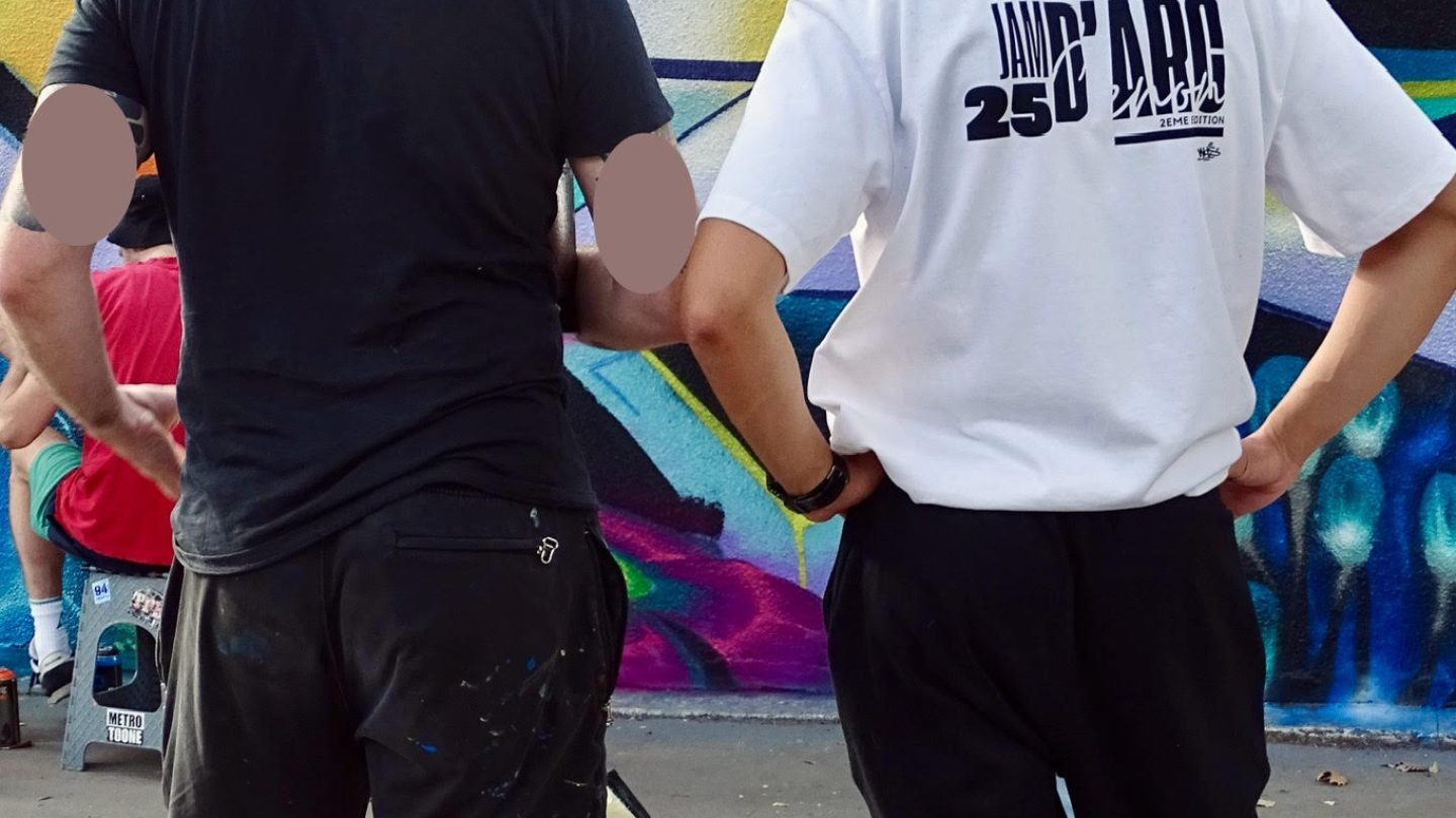 Artiste et organisateur observant et analysant une fresque graffiti en cours pour ajuster la composition