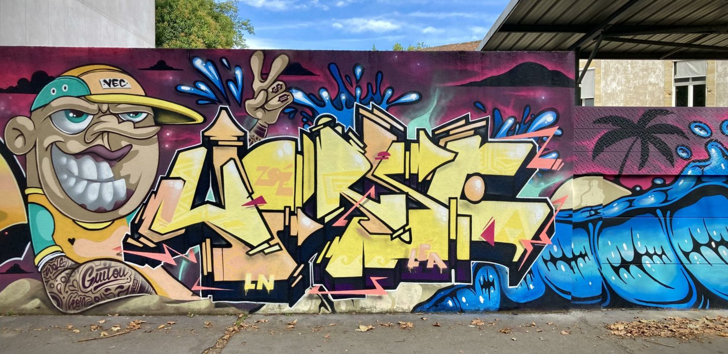 Fresque graffiti collaborative avec lettrage jaune et effets graphiques colorés.