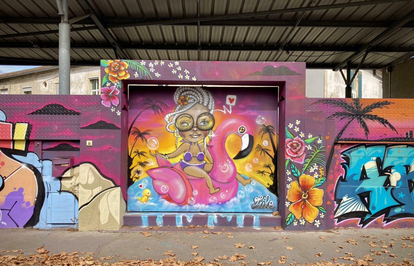 Personnage street art représentant une femme sur une bouée flamant rose dans un décor tropical.
