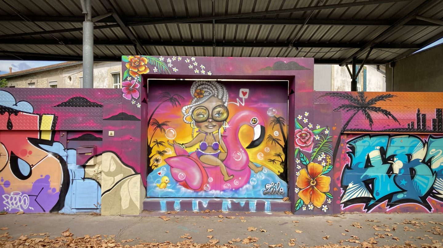 Personnage street art représentant une femme sur une bouée flamant rose dans un décor tropical.
