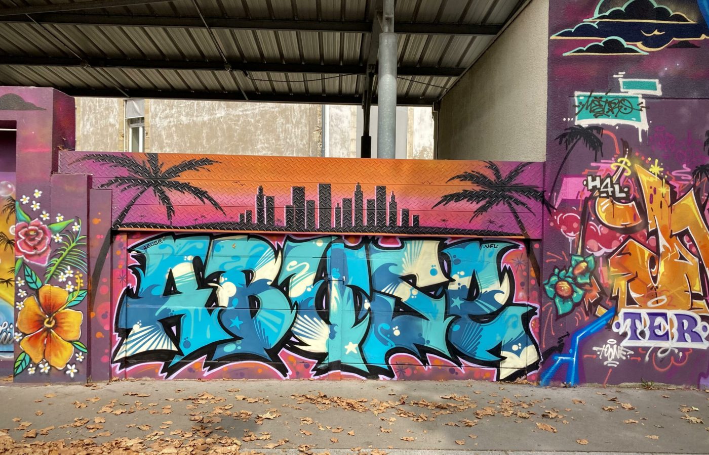 Lettrage graffiti avec skyline urbaine et fond coloré dégradé.