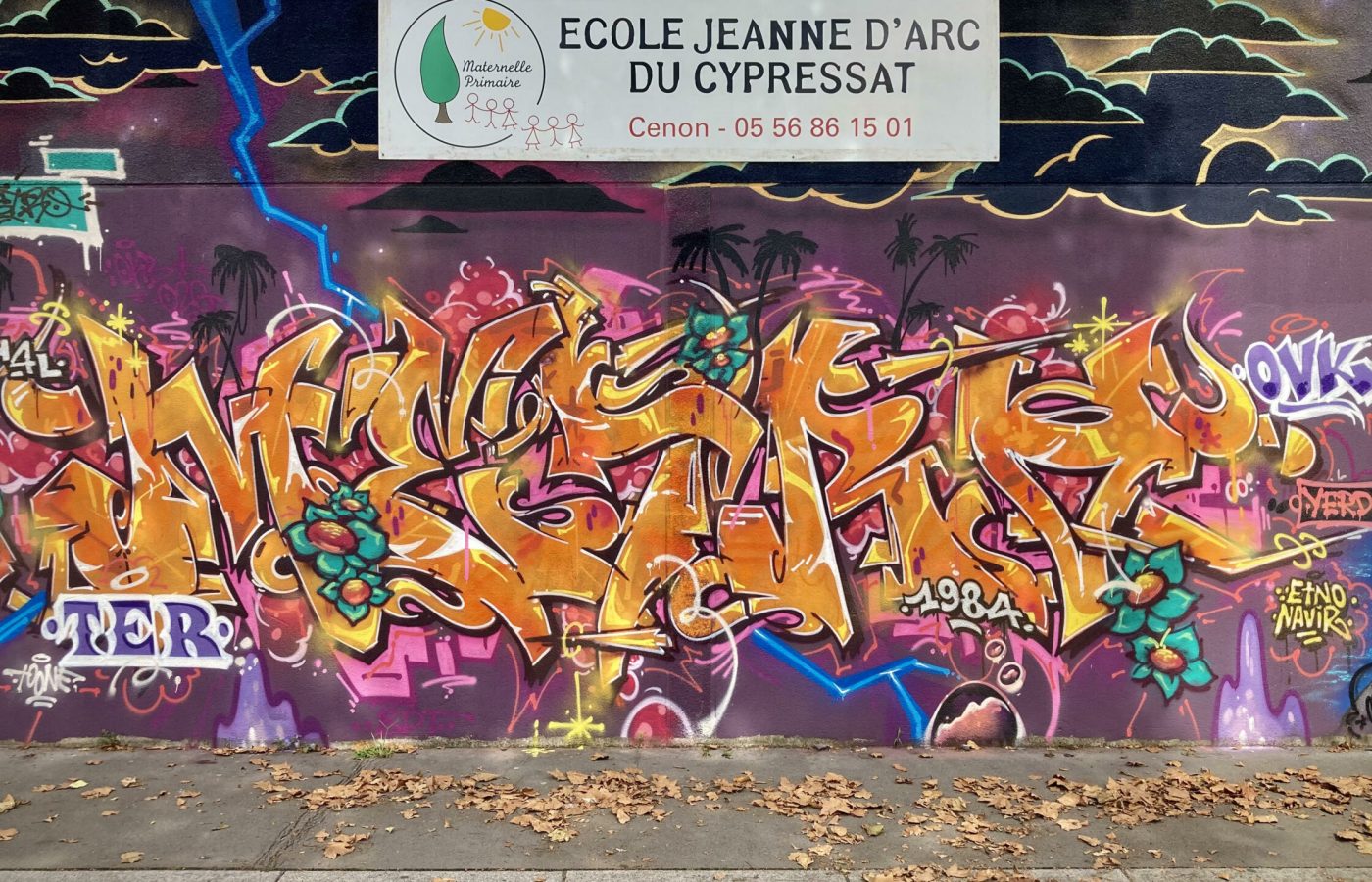 Fresque graffiti colorée avec lettrage dynamique sur mur d’école à Cenon.