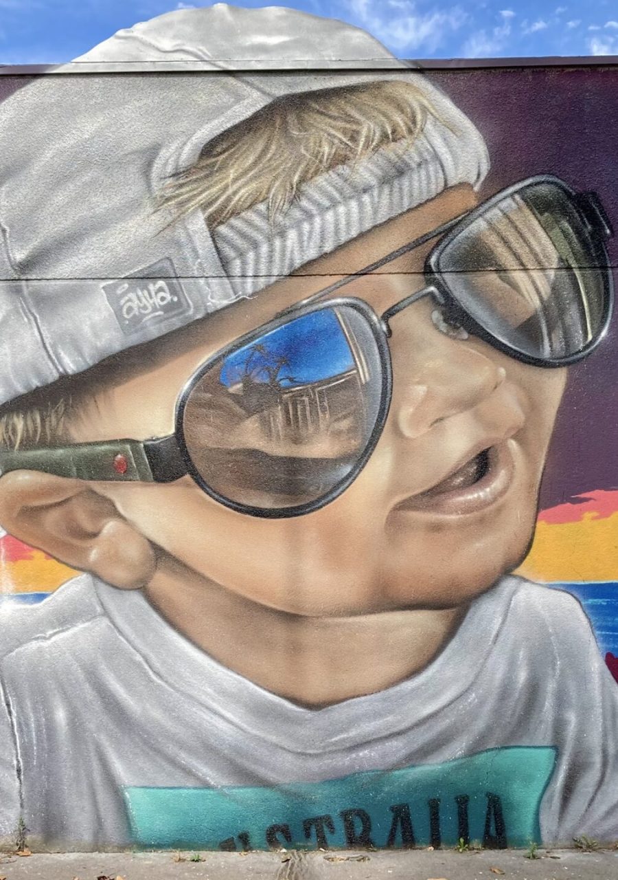 Portrait graffiti réaliste d’un enfant avec lunettes de soleil sur fresque Laguna Beach réalisée lors de la JAM D’ARC 2024 à Cenon.