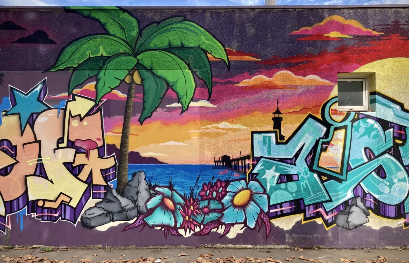 Fresque graffiti avec palmier, océan et lettrage coloré.