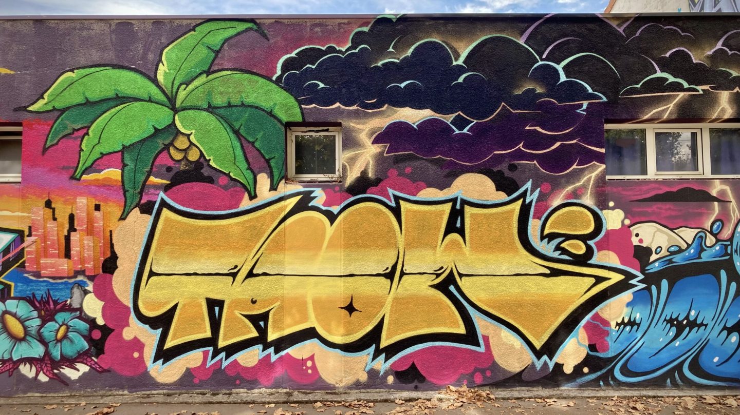 Lettrage graffiti doré avec nuages et éclairs en arrière-plan.