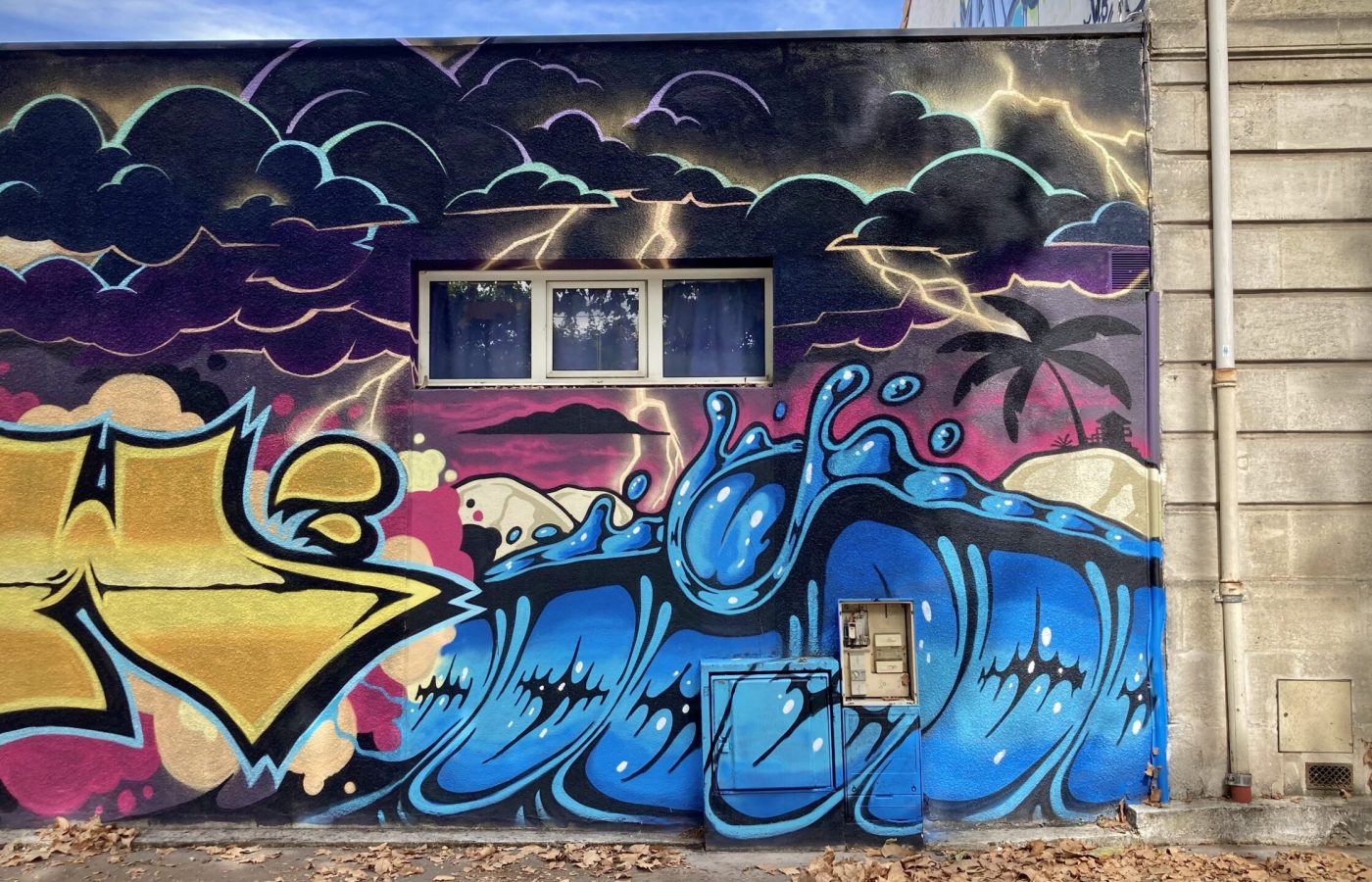 Fresque graffiti représentant une vague stylisée avec ciel orageux.